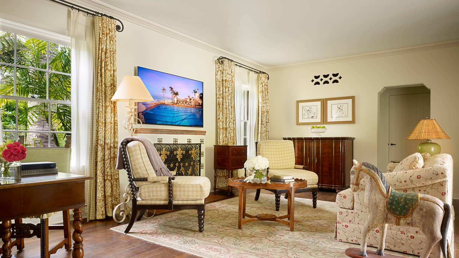 Bungalow Suite sunny living room with yellow plaid accent chairs, floral sofa, rocking horse statue