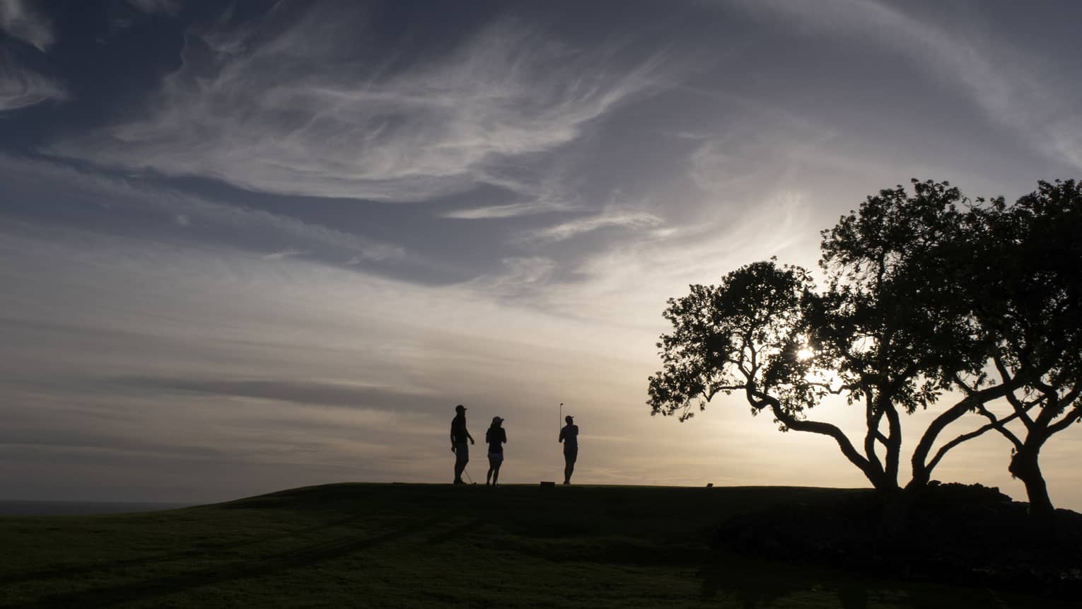 Golfers at Four Seasons Resort Lanai golf course at sunset