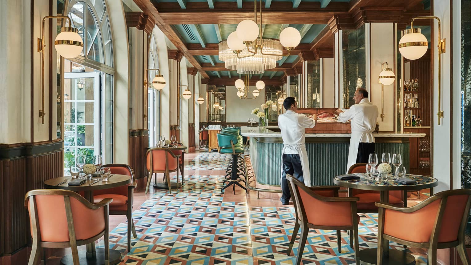 Pink dining chairs, wood tables, colourful tiles in bright Zanaya Restaurant dining room