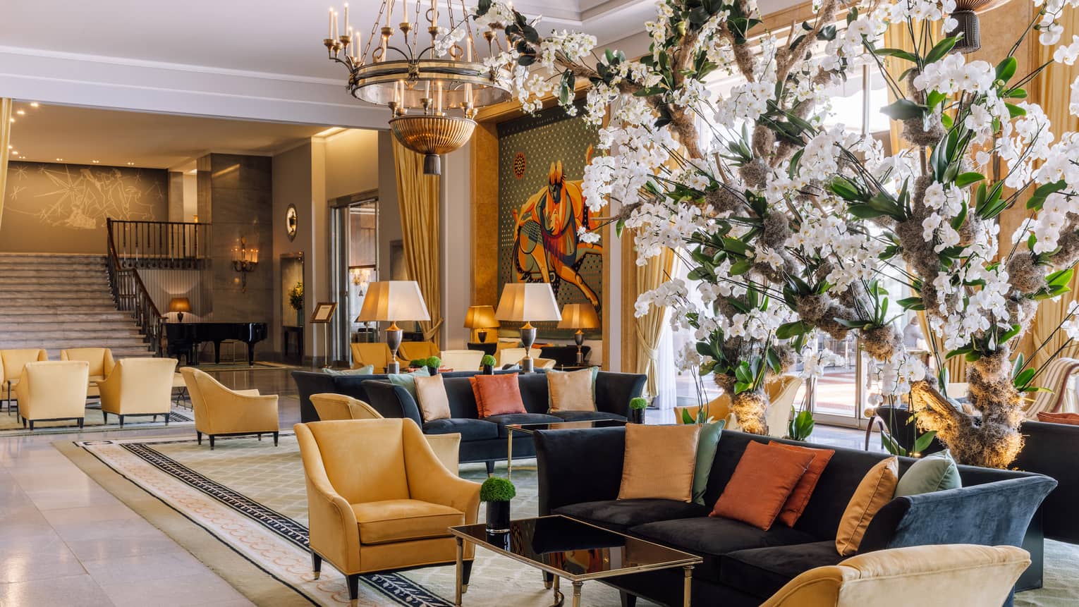 A lobby area with sofas, chairs and white flowers.