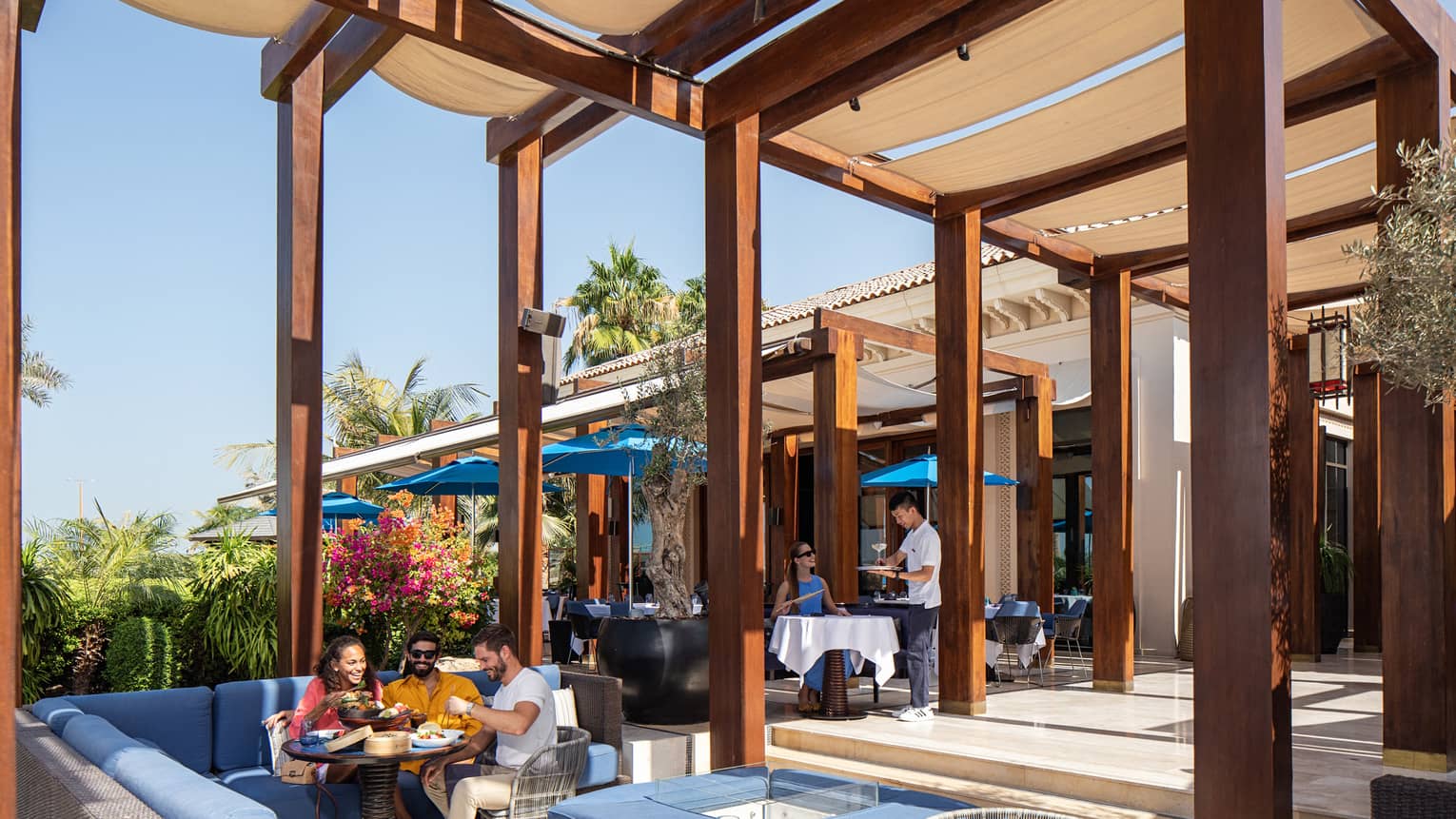 Several people dine outside in a covered patio.