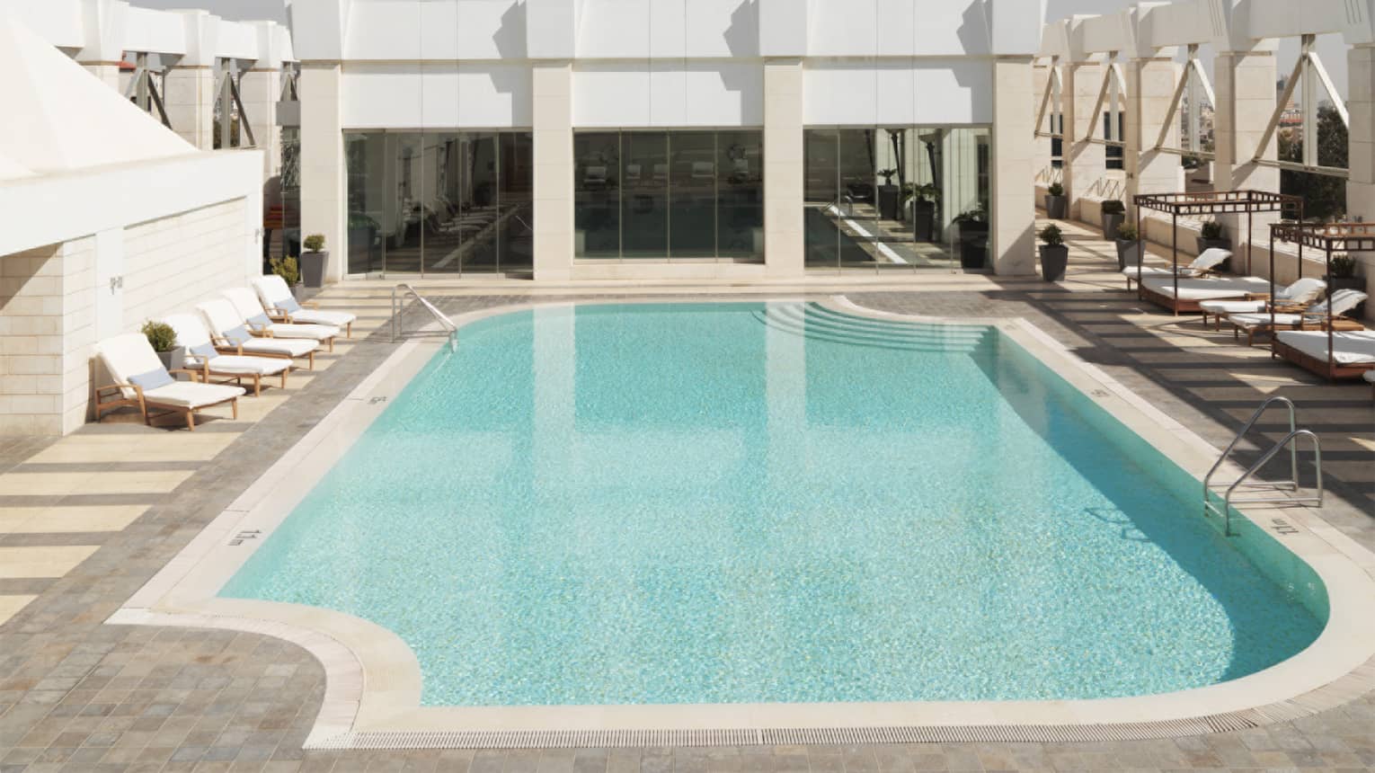 Aerial view of tall white building with blue swimming pool on sunny day