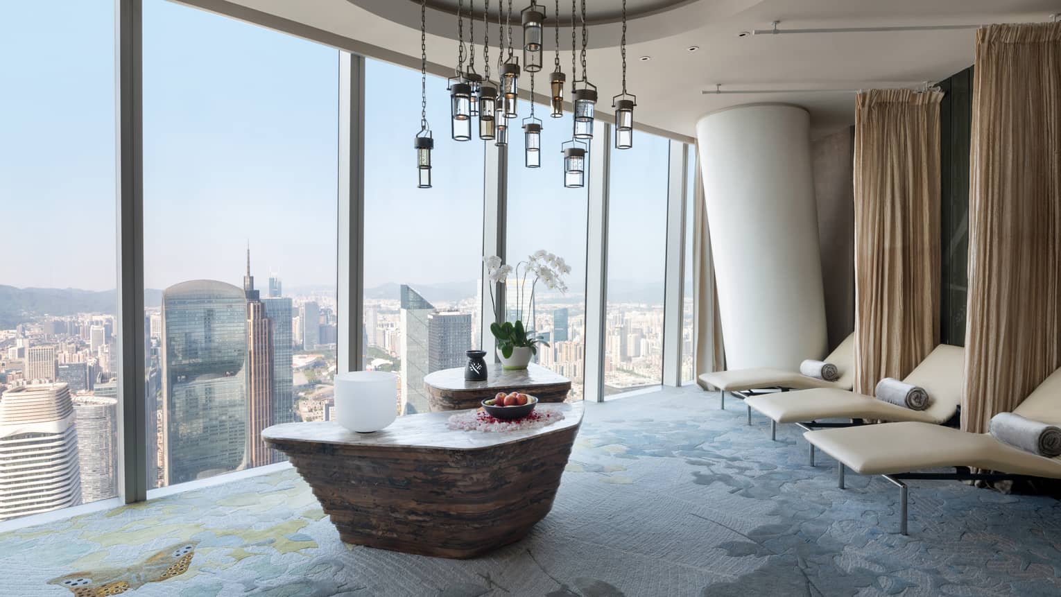 Large soaking tub filled with flower petals overlooking the cityscape from floor-to-ceiling windows