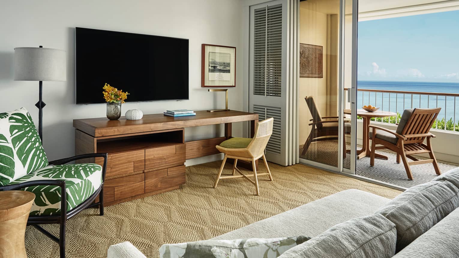 Oceanfront Suite large rustic wood desk under TV, palm print chair, open balcony doors