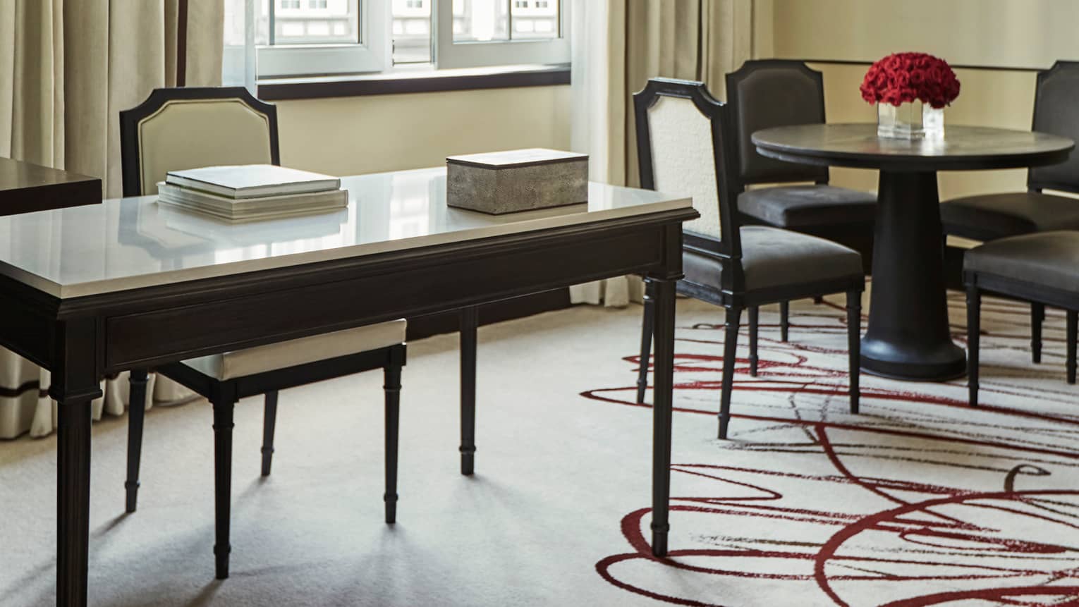 Hotel suite modern white desk, chair with books by cafe dining table with red roses, sunny window