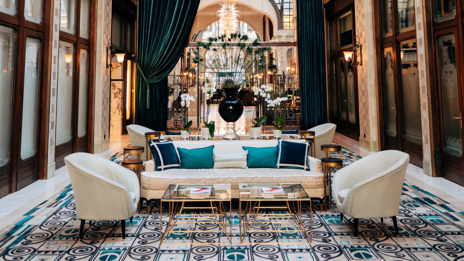 Zrínyi Passage with Zsolnay tiles, white chairs and couch, blue cushions, drapes and high ceiling