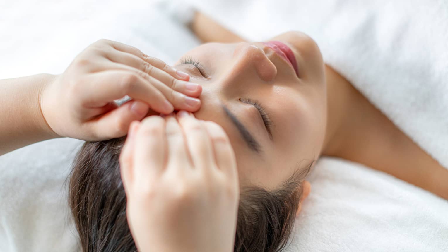 A woman getting a facial massage in a spa.