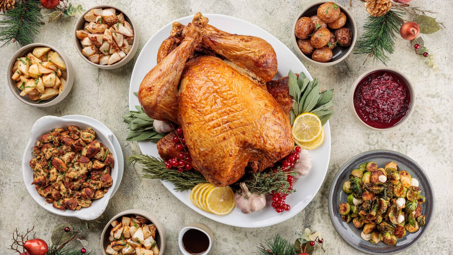 Whole roasted turkey set surrounded by seven small plates of holiday side dishes
