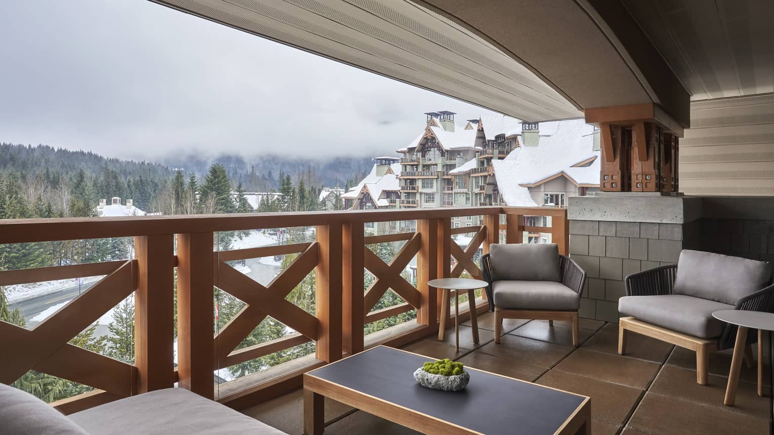 Large balcony with a sofa, two arm chairs and a coffee table overlooking Whistler resort