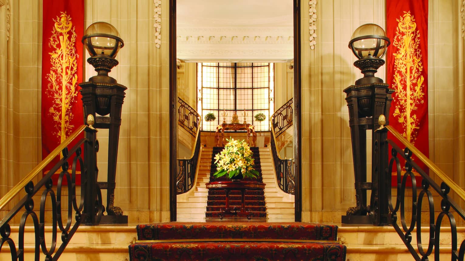 Intricate ceiling mold and a red carpet line the entrance to La Mansion