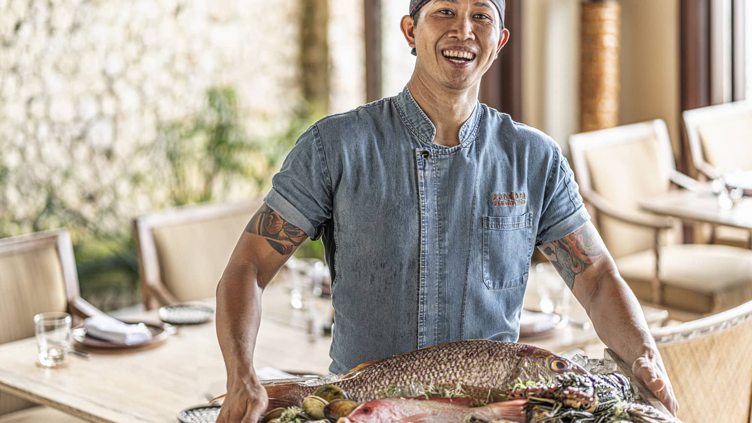 Smiling chef holding platter of fresh seafood