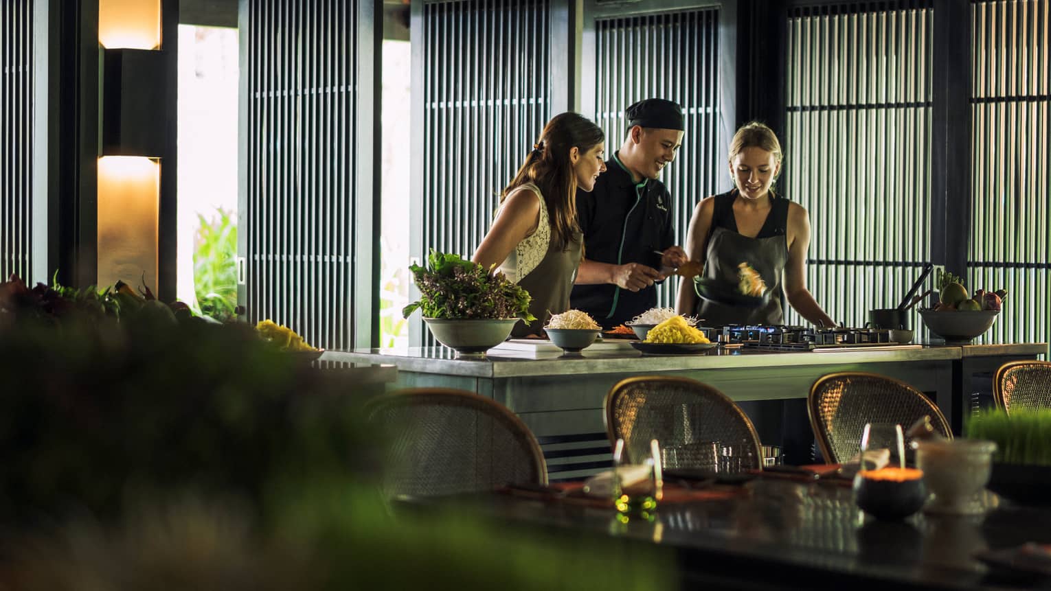 Chef, two women look at pan on kitchen range at Hoi An Cooking Academy