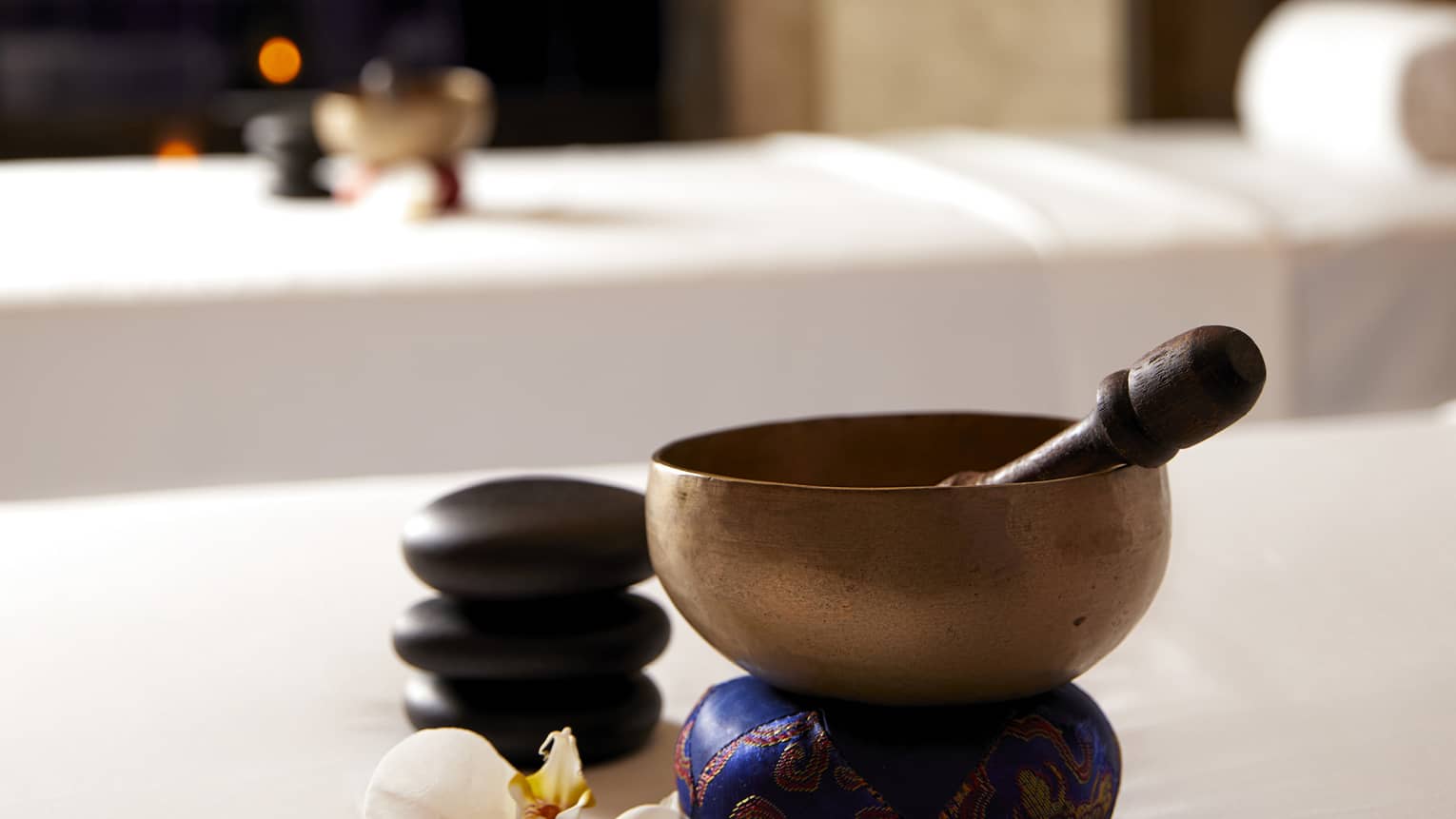 Copper bowl and wood spoon on couples spa treatment beds in spa