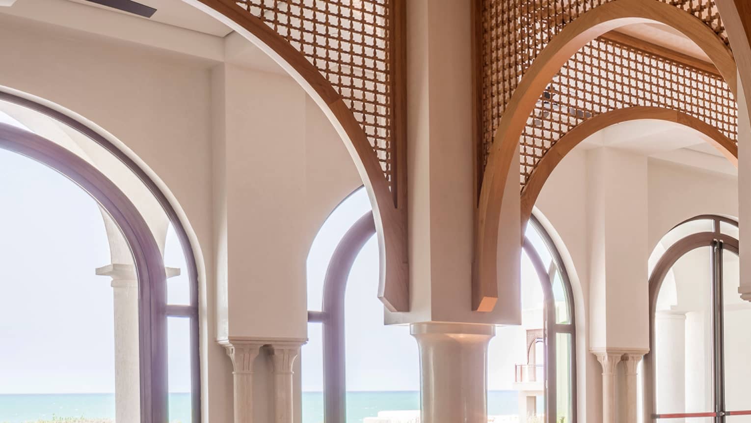 Restaurant dining area with archways, set square tables, tan leather dining chairs, water view