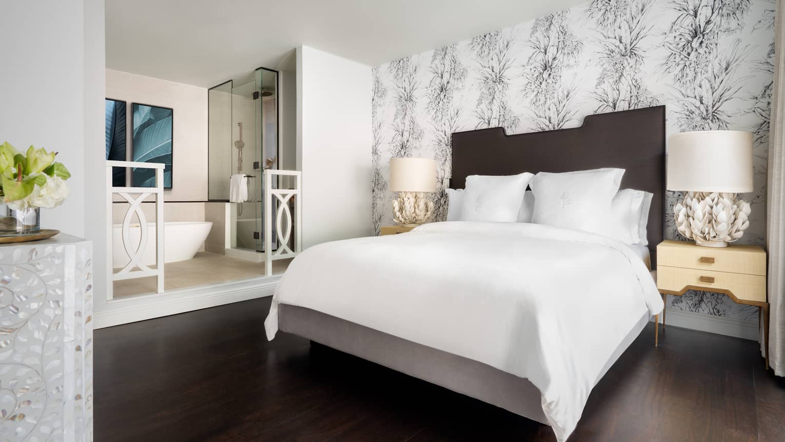 Resort room with a queen bed, modern decor and an open bathroom featuring a freestanding bathtub