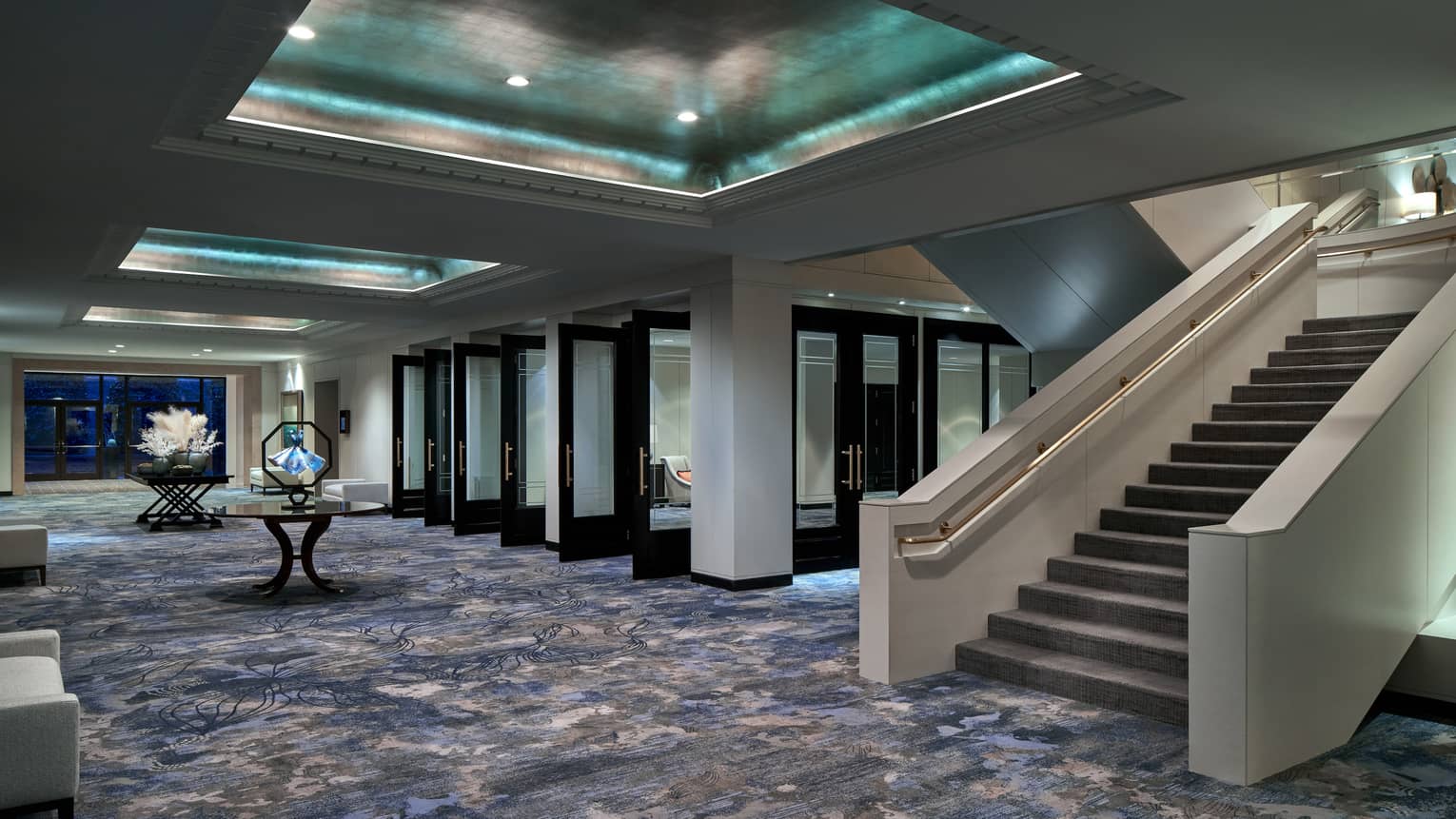 Events hall with blue-ish carpeting, grand staircase and inset metallic ceiling with recessed lights