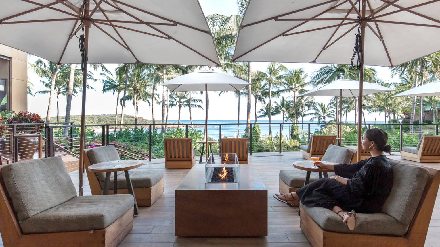 Woman sits on lounge chair outside on Hawaiian terrace