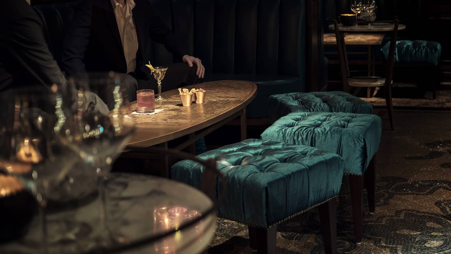 Close-up of men drinking cocktails on lounge table in dimly-lit Charles H dining room