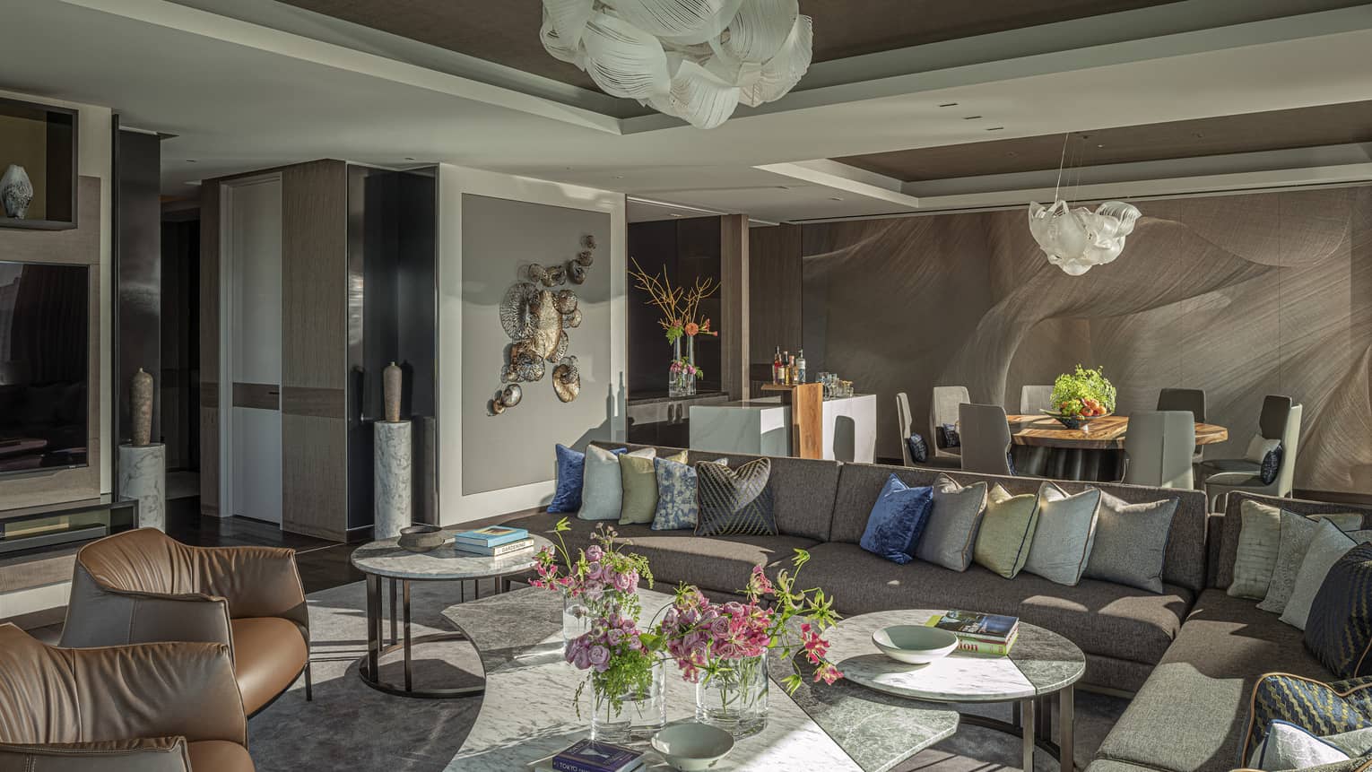 Elegant living room with large sectional sofa with many pillow, two leather chairs and dining table
