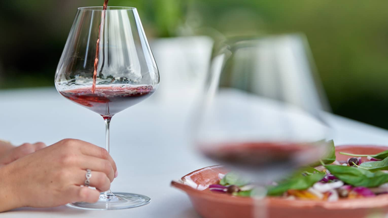 Hand pouring red wine in decanter into a wine glass