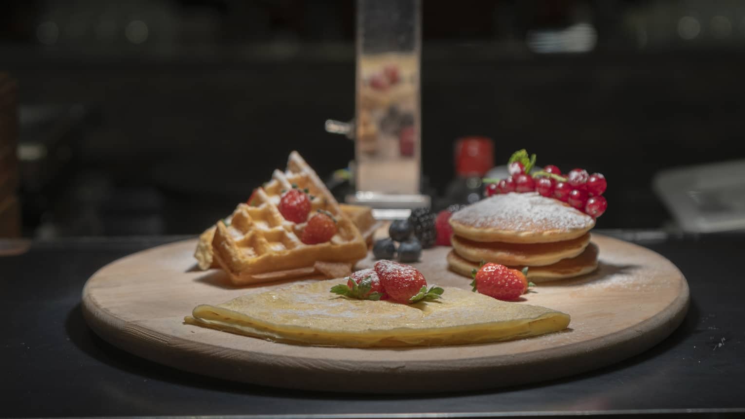 Waffles, pancakes and cr�pes with berries on a round tray under a heat lamp