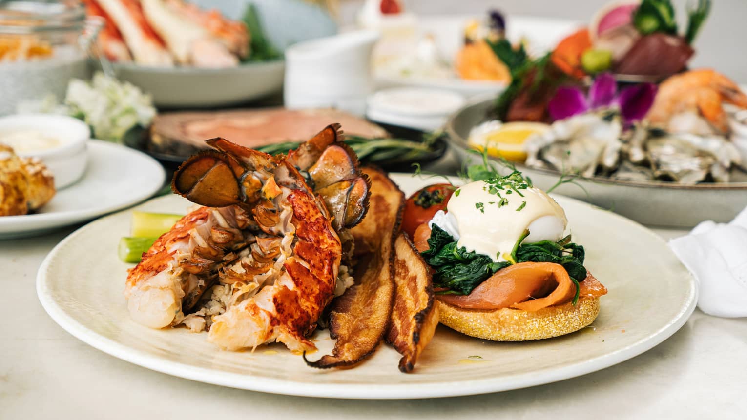 Brunch spread, focusing on a plate with lobster, bacon and Eggs Benedict