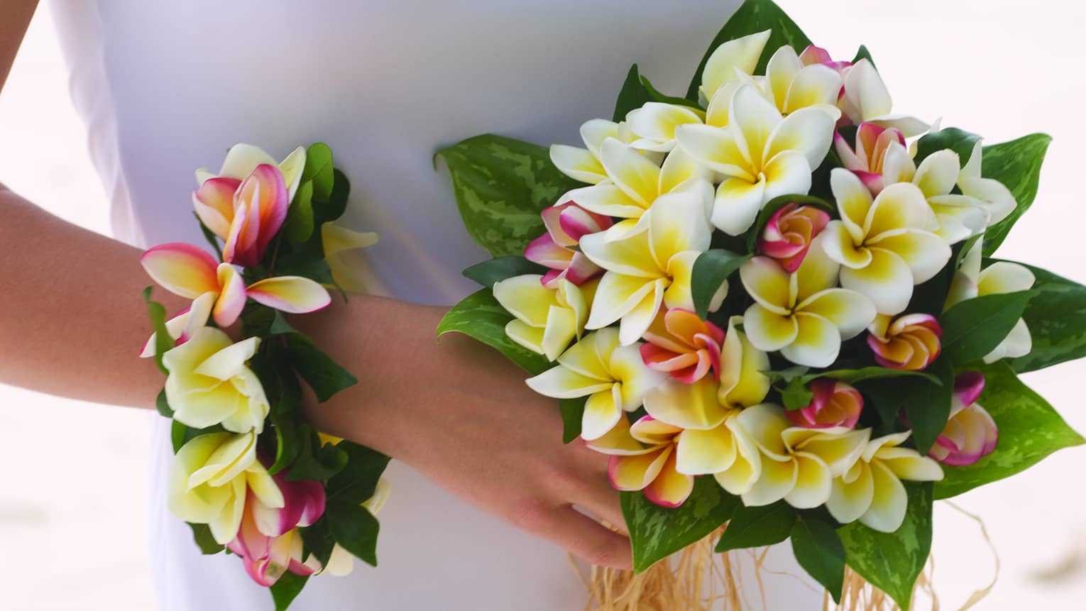 Bride holding wedding bouquet and floral wristband with tropical flowers
