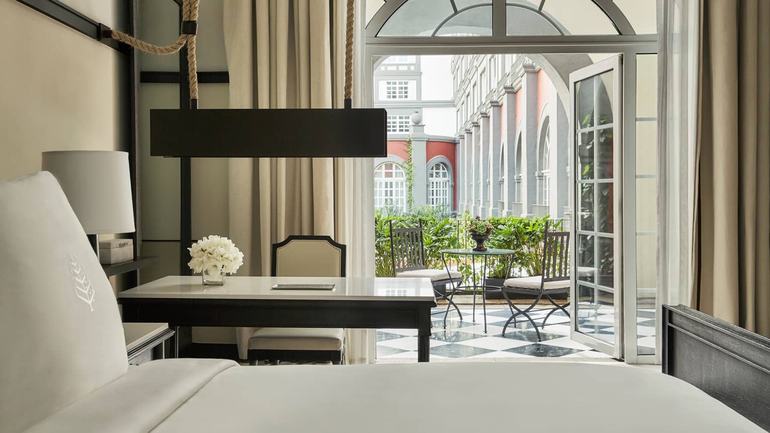 Premier Terrace Room bed, white desk and chair by open French doors to balcony