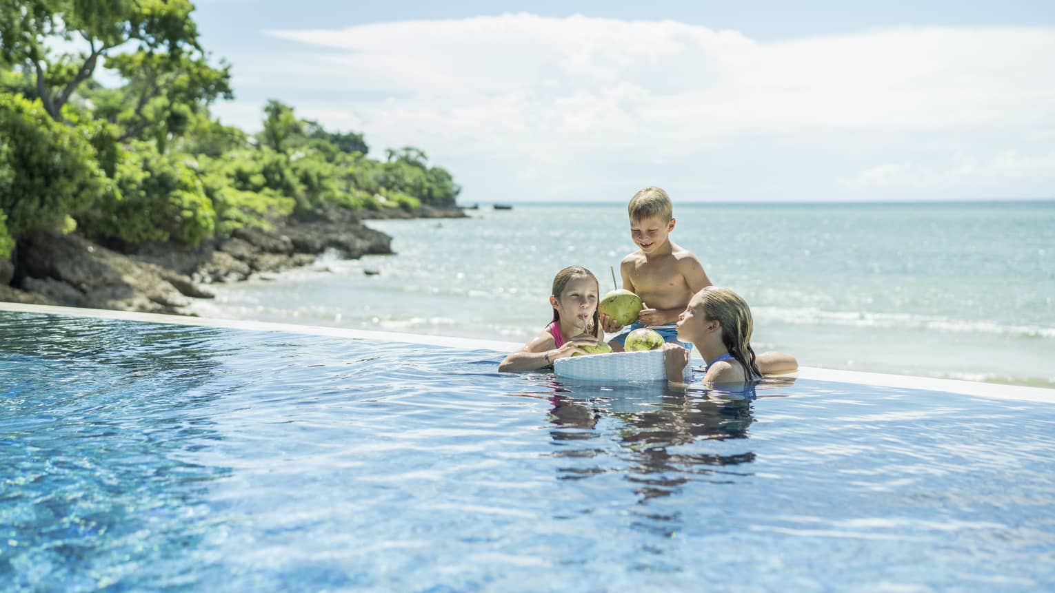 Two girls and a boy relax in the wading pool by the beach