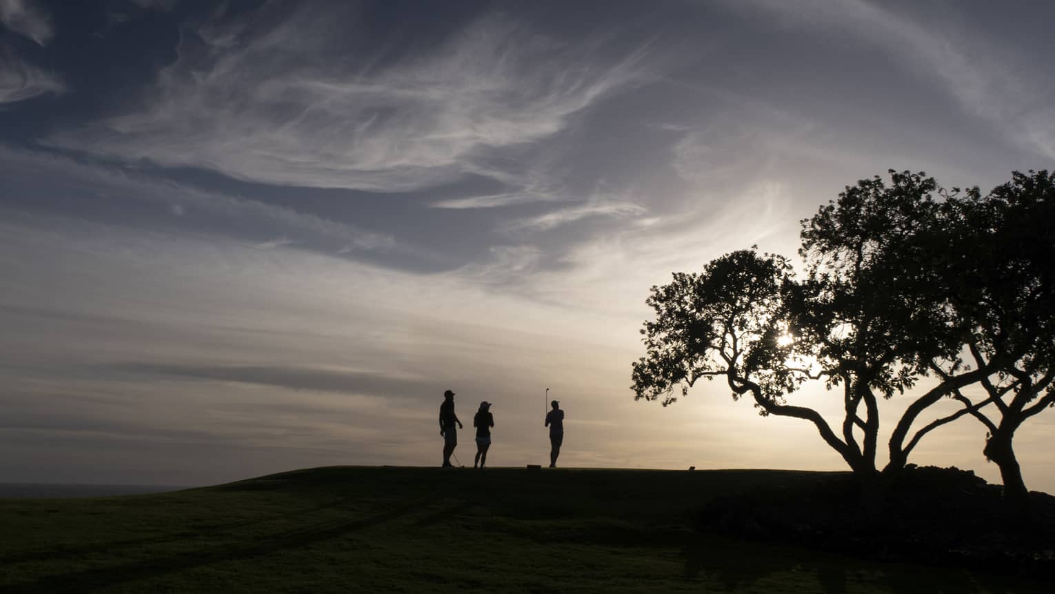 Golfers at Four Seasons Resort Lanai golf course at sunset