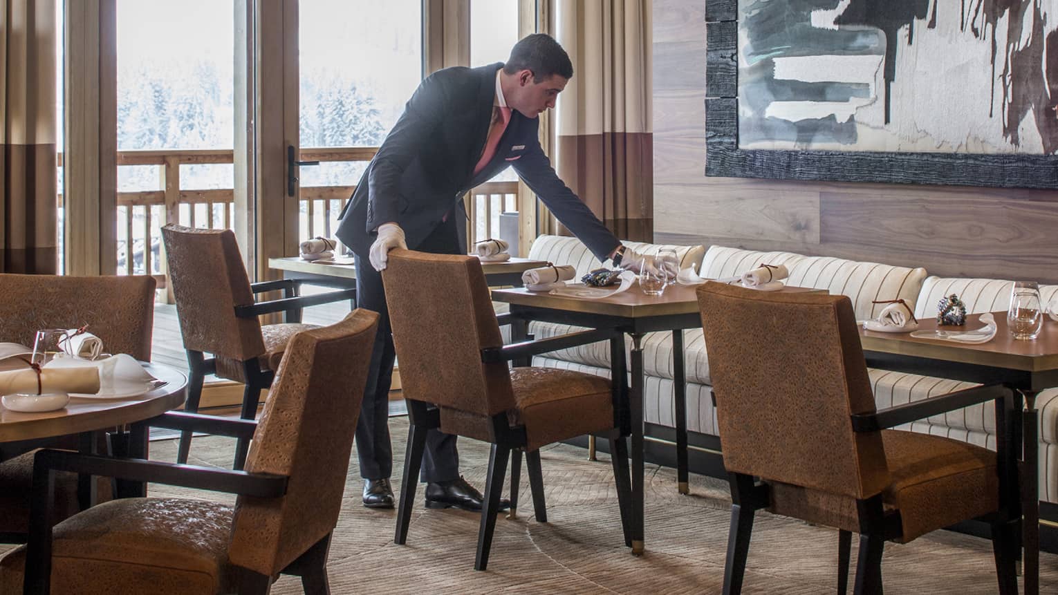 Server sets dining table under large, framed abstract painting in Le 1920 restaurant
