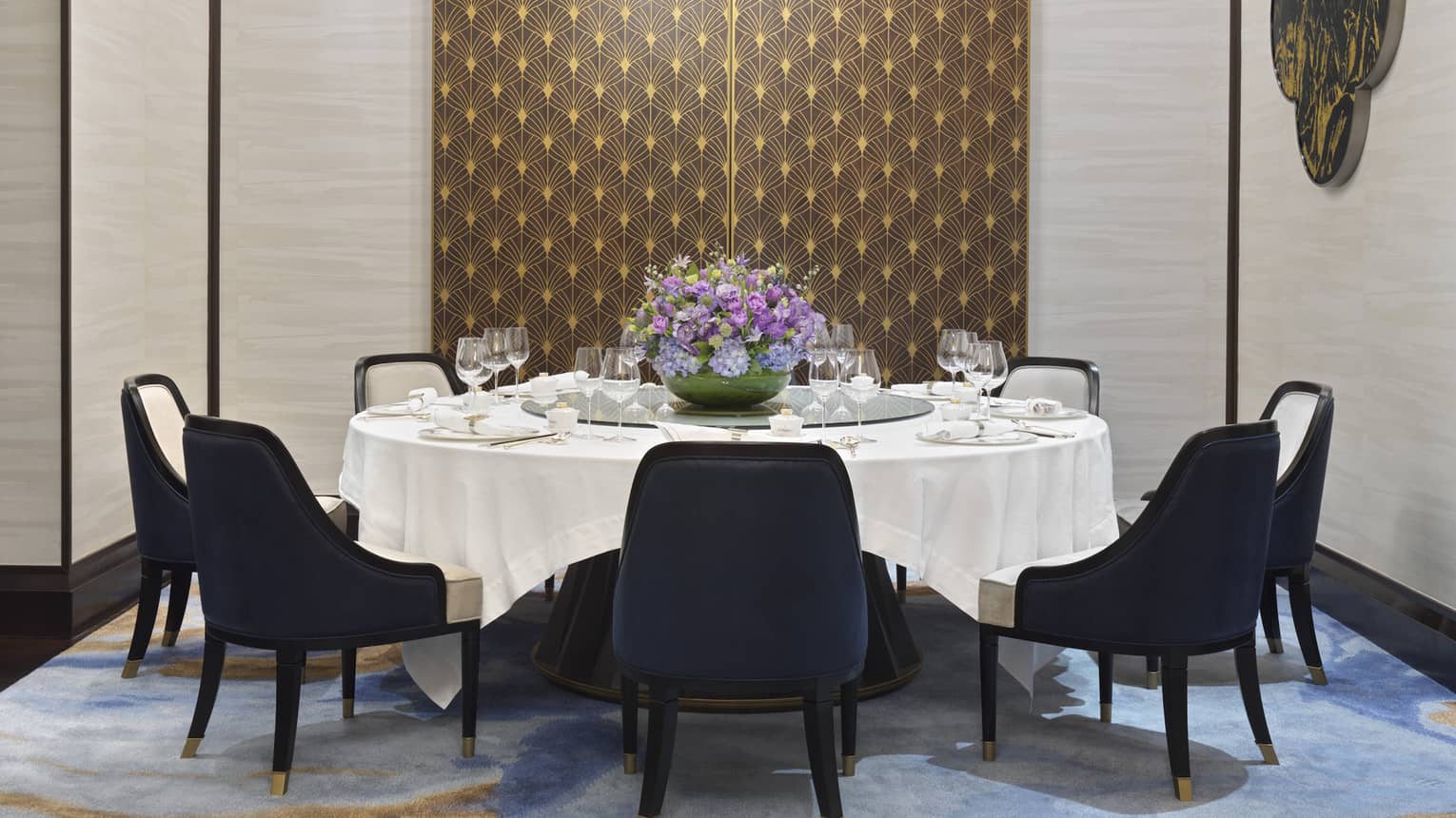 Zi Yat Heen private dining room with round table and white linens, eight blue chairs, watercolour carpeting, triple light fixtures from ceiling