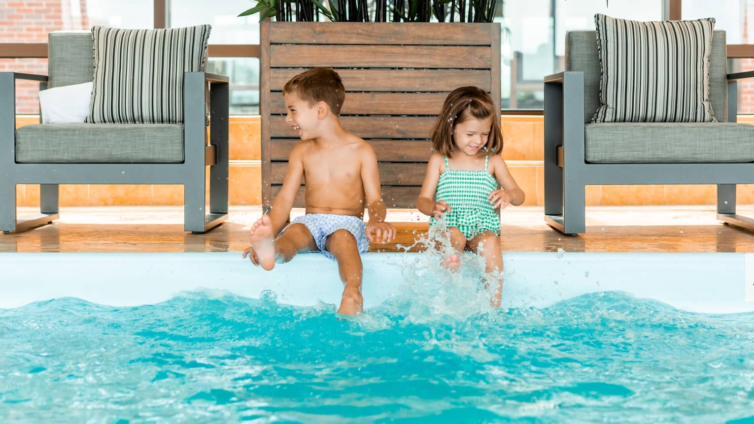 Two young children sitting on the edge of a pool.