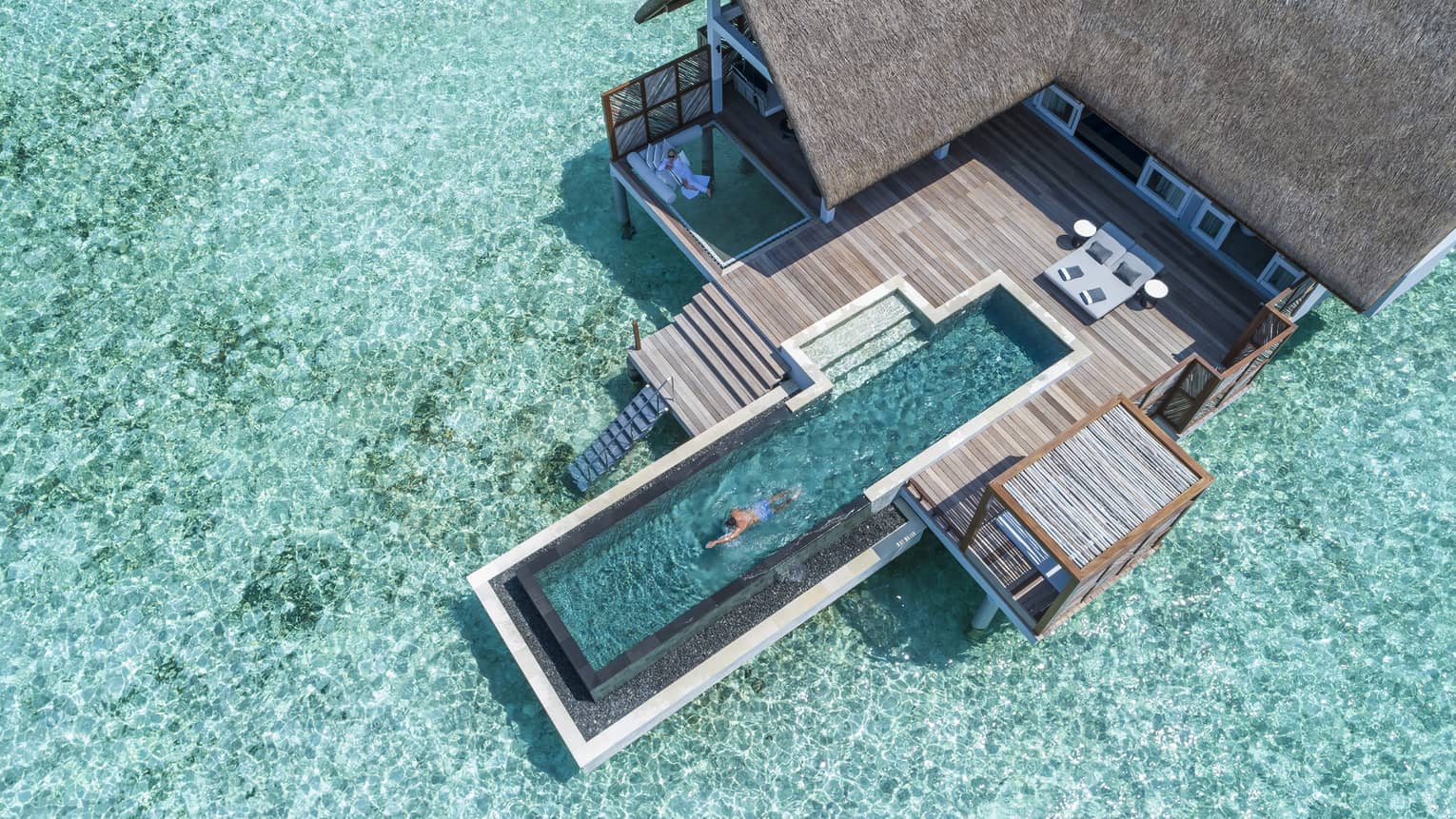 Aerial view of water villa with long swimming pool over lagoon