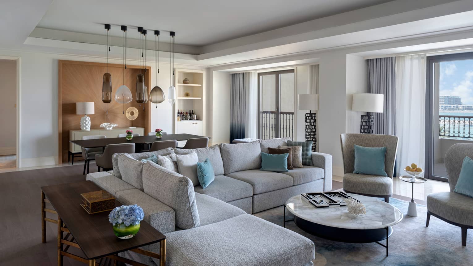 Living room with large grey sectional sofa, dining table in the back