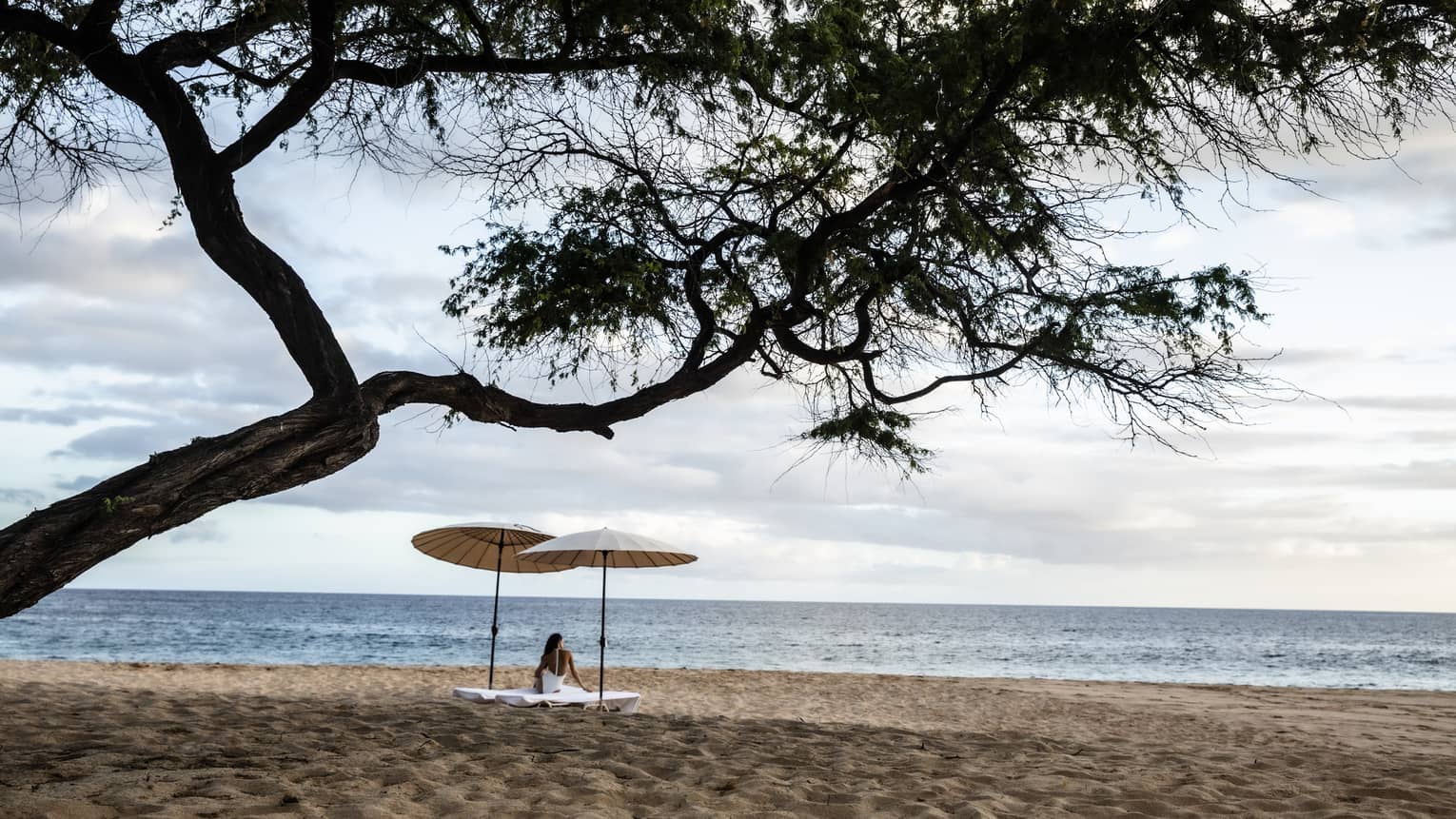 Woman under two umbrellas at tropical Hawaiian beach