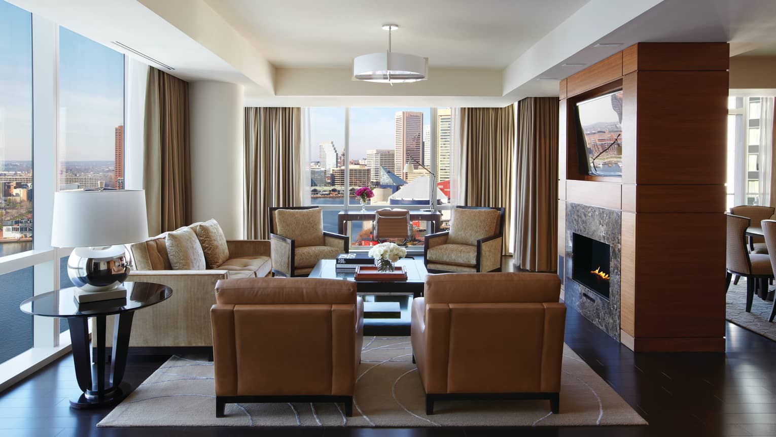 Serene Suite brown leather armchairs, sofa, chairs around gas fireplace, corner windows