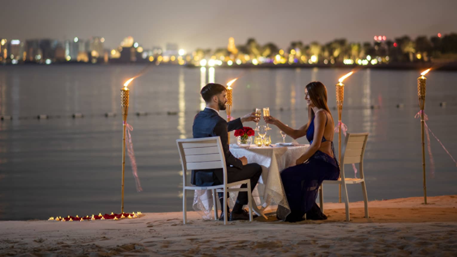A couple dines along the gulf with the Doha city skyline in the background.