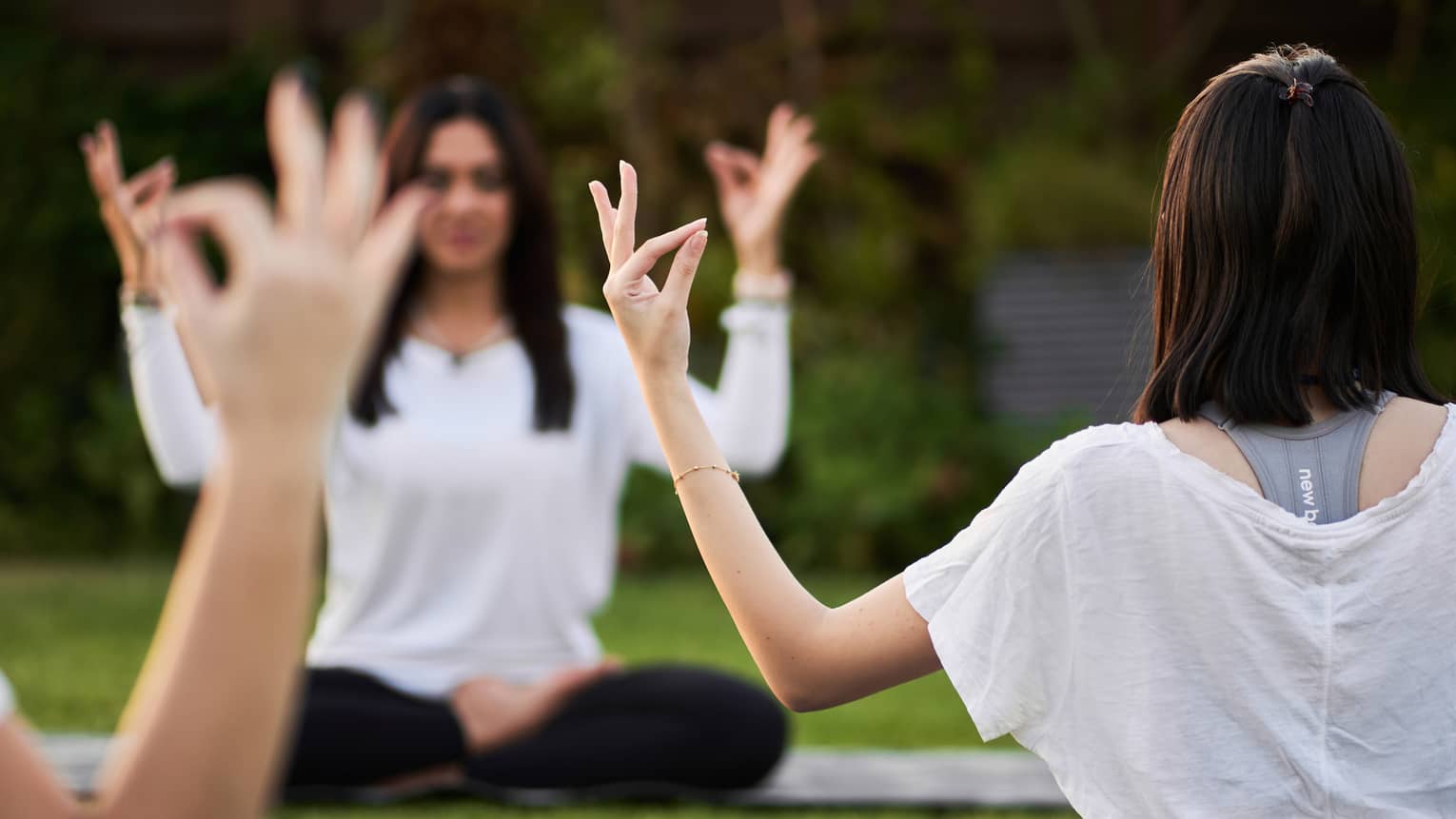 Guests doing yoga outdoors on yoga mats with trees in the background
