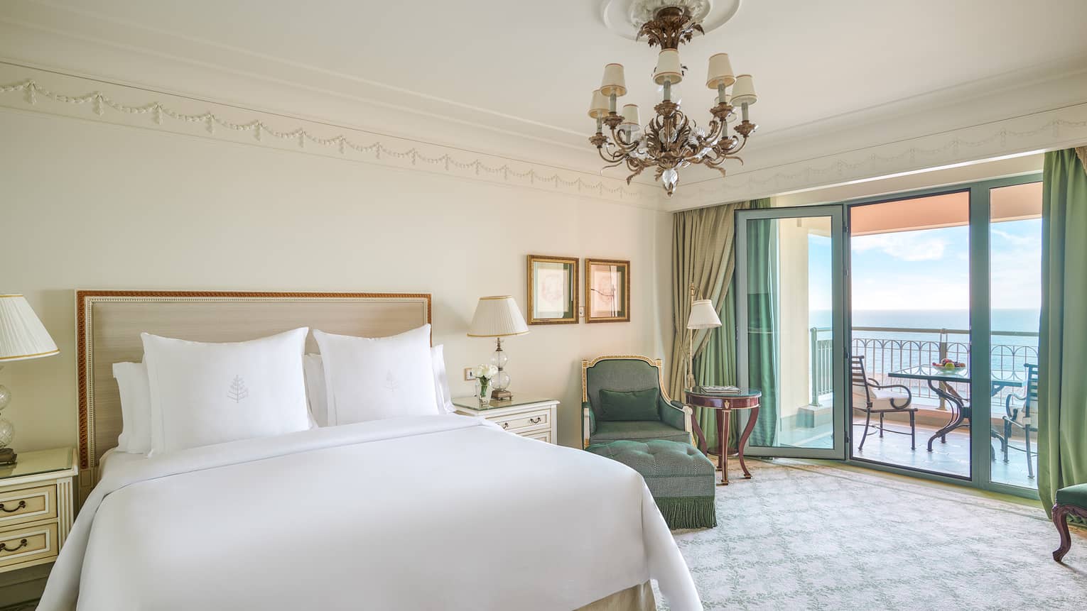 Sea View Suite bedroom with king bed, green chaise longue, glass door to veranda