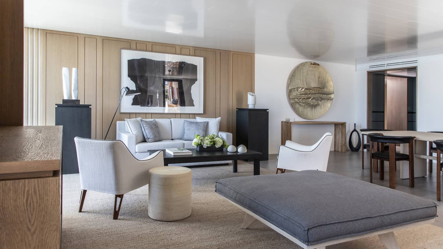 Beach-chic living room with a sofa, two arm chairs, a large ottoman with a grey cushion