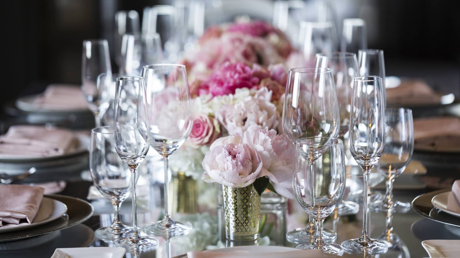 Pink roses, empty wine glasses arranged on long wedding banquet table
