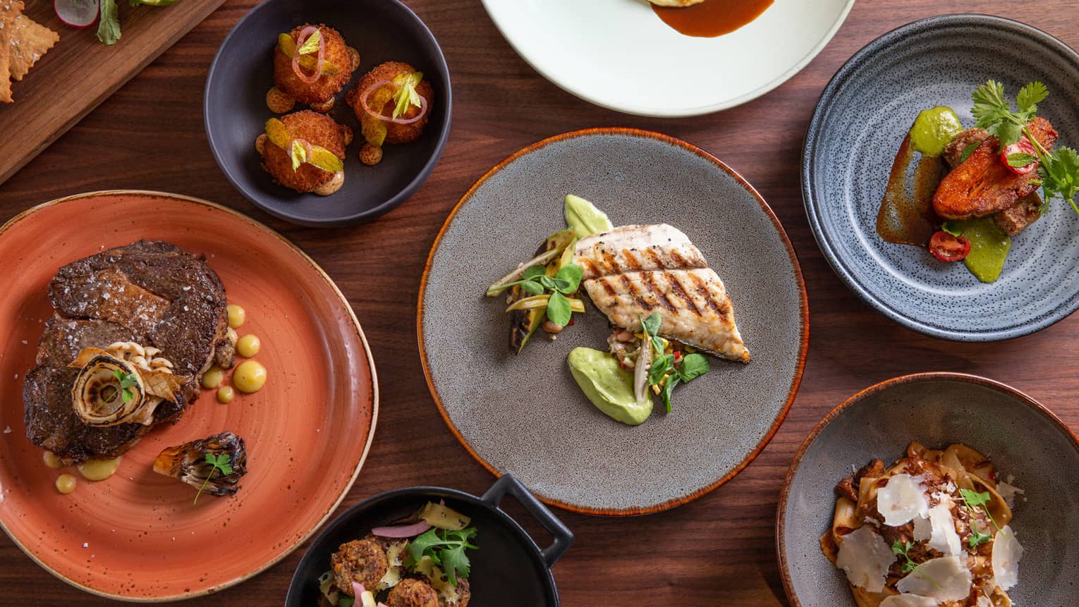 Aerial view of dinner plates on table with large grilled chicken breast, steak 