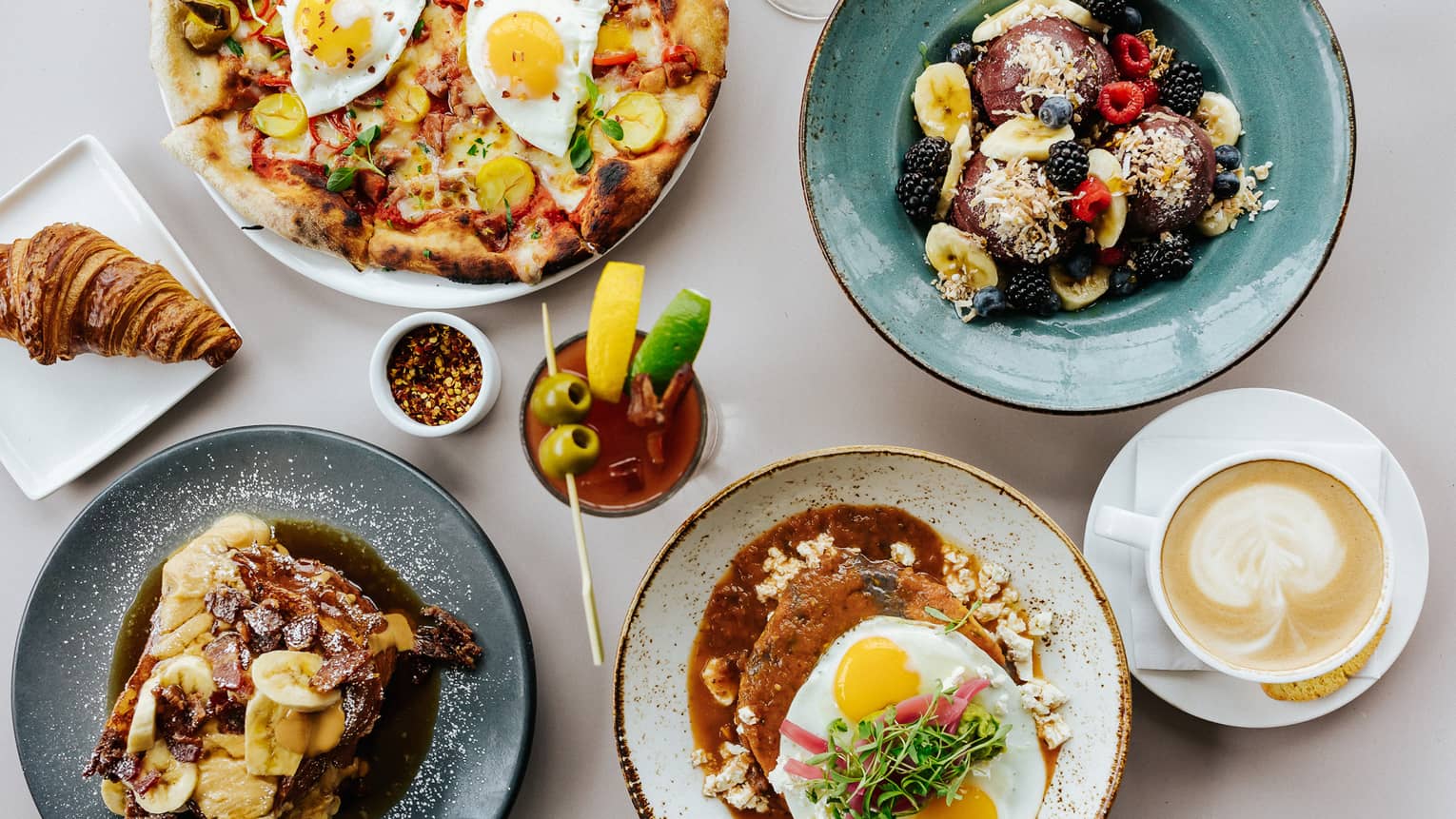 An array of colourful plates containing a variety brunch dishes, along with beverages