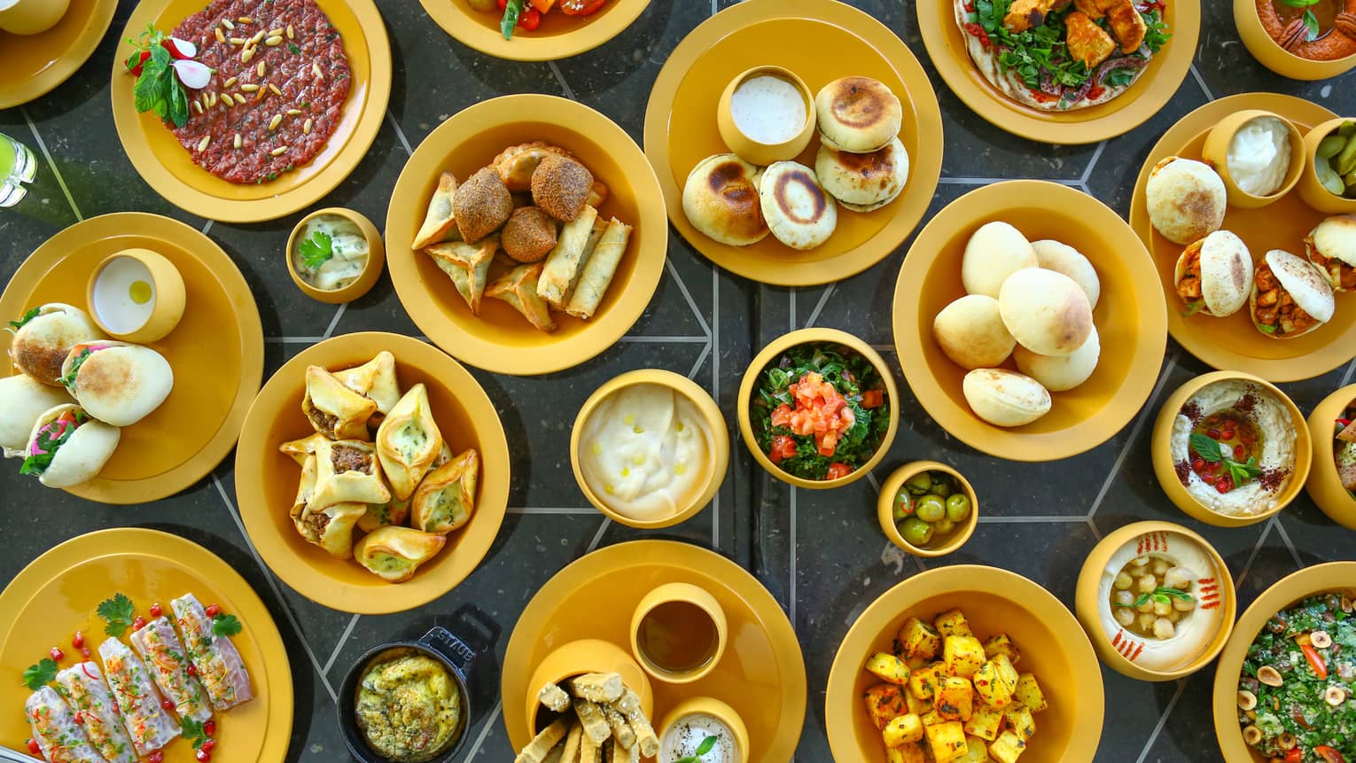 Various small plates and bowls of Lebanese food spread across a table