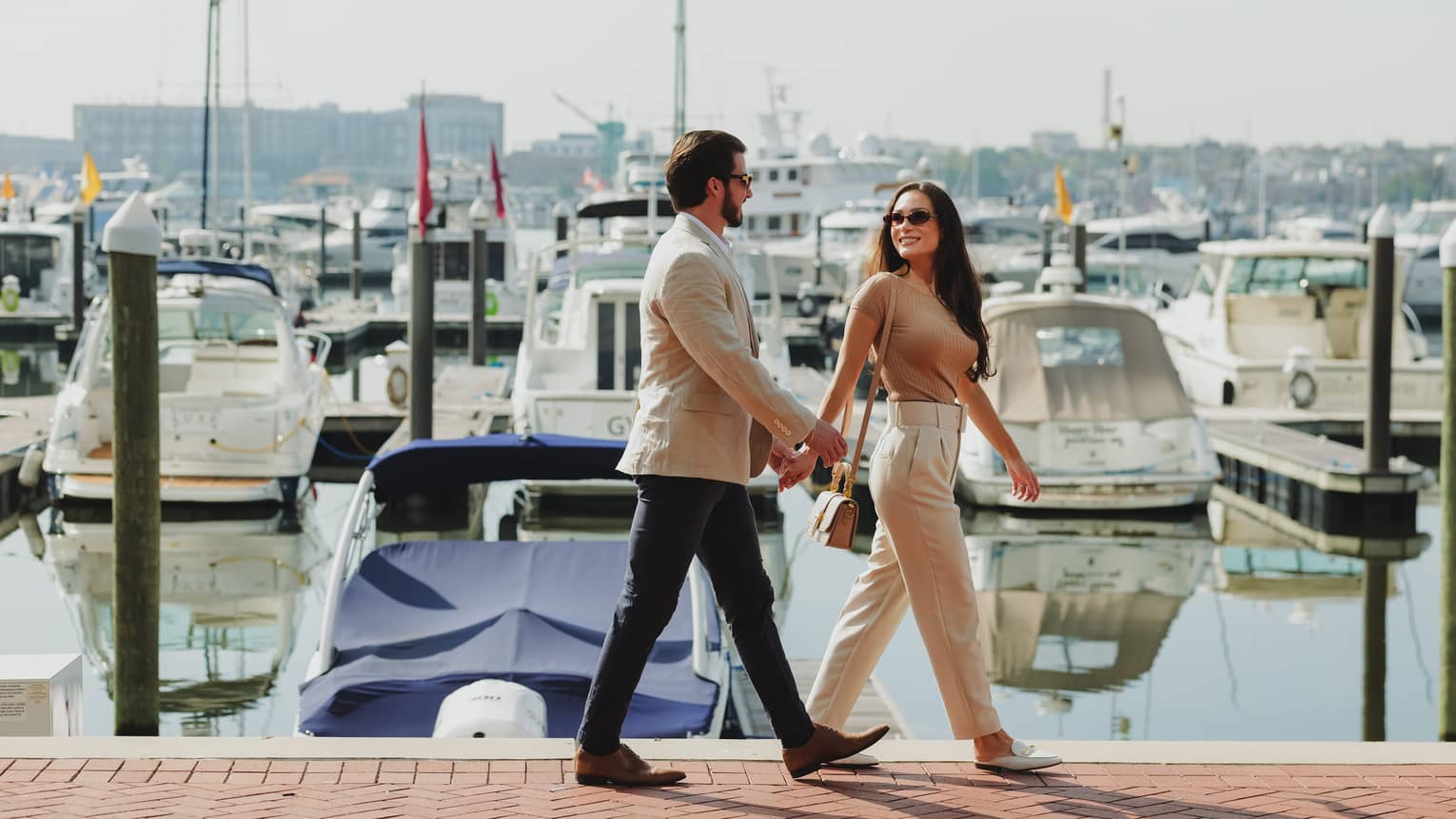 Two guests walking together near a waterfront with boats in the water