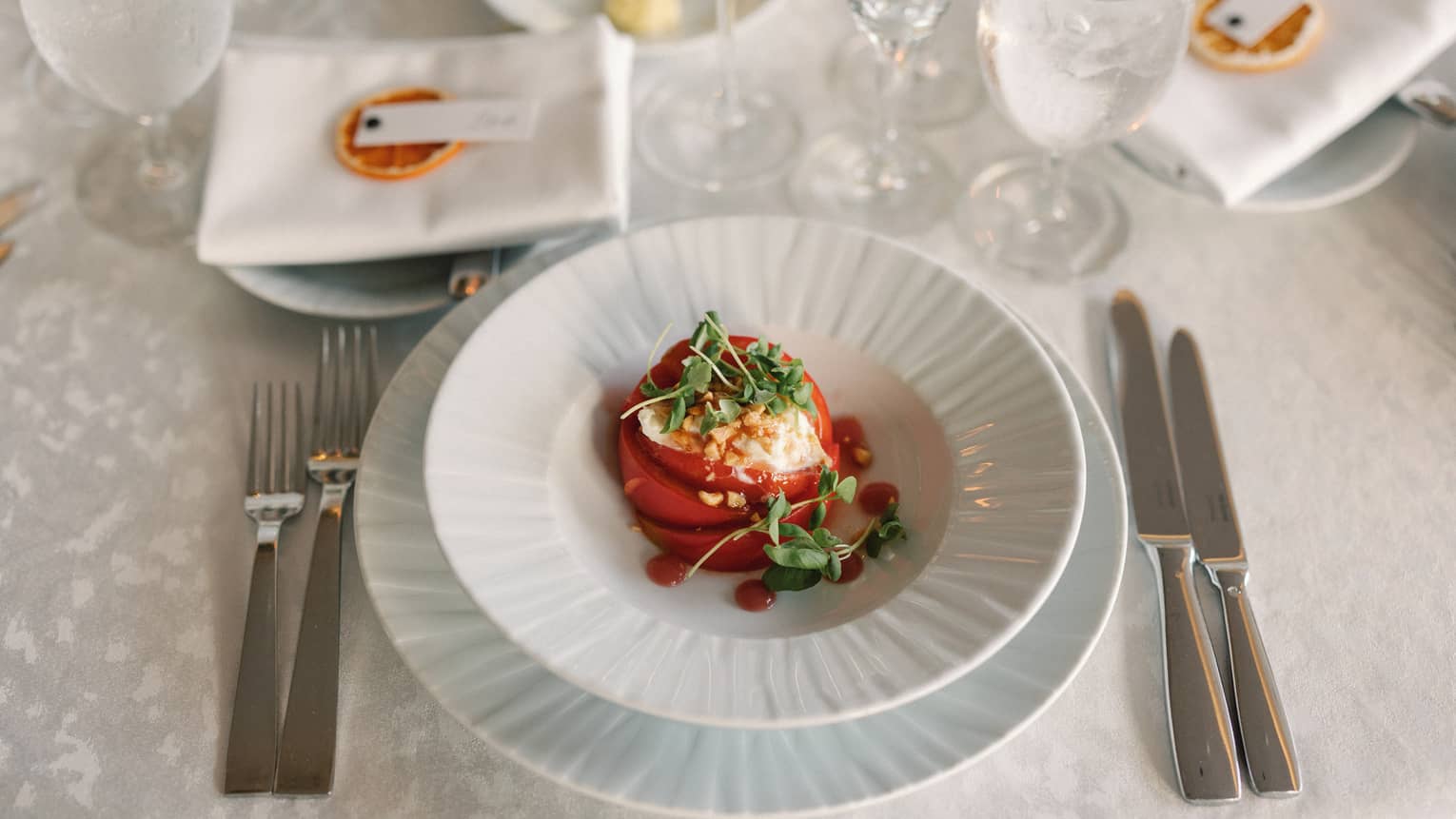 A plate of food on a table with utensils and four wine glasses
