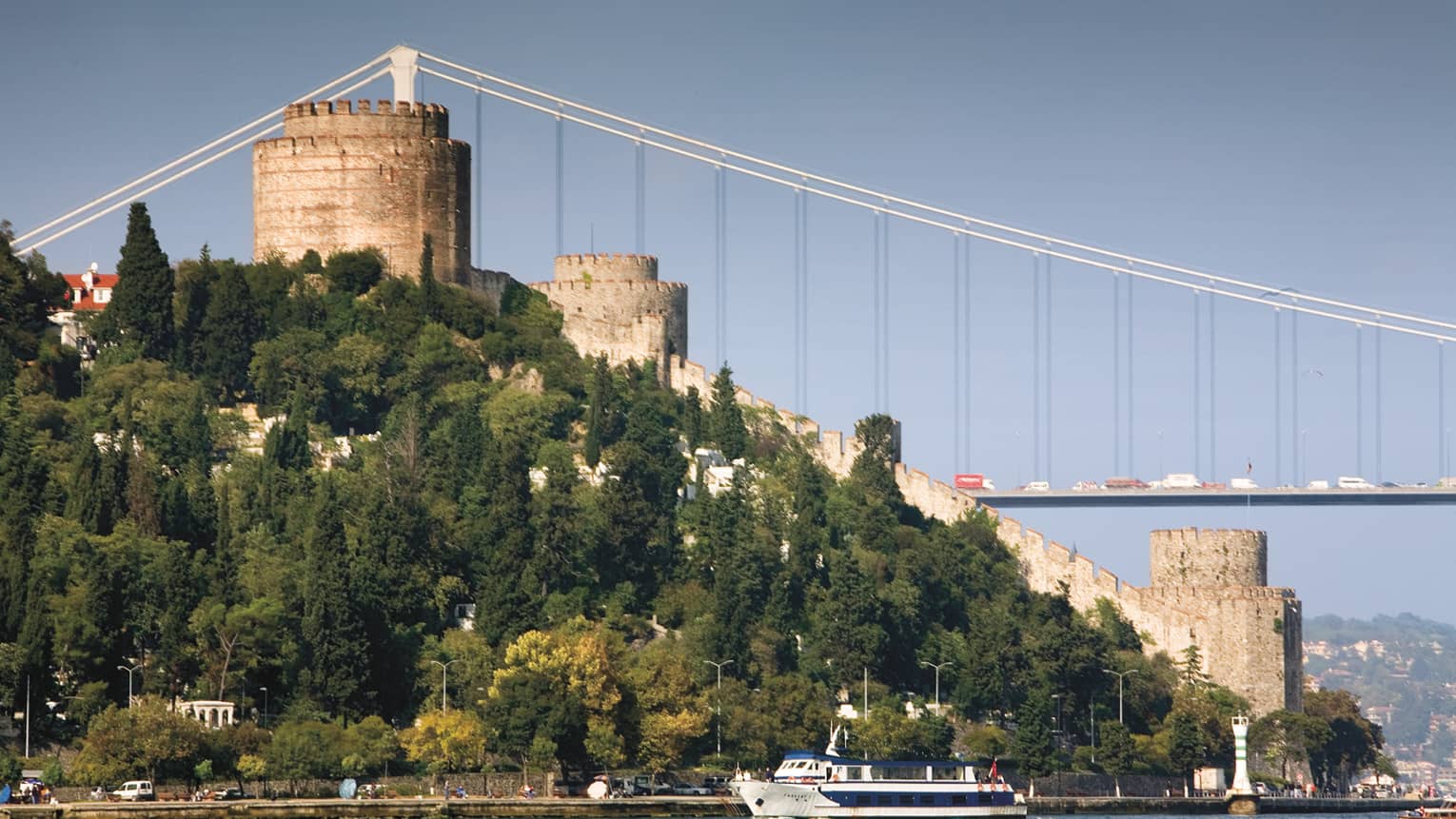 Bridge over sea, behind large grassy hill in Istanbul