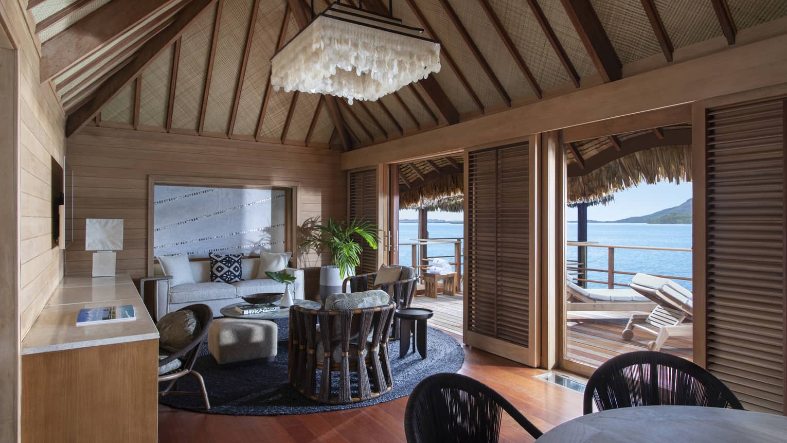 Dining and living area of a thatched-roof bungalow, opening up to private terrace