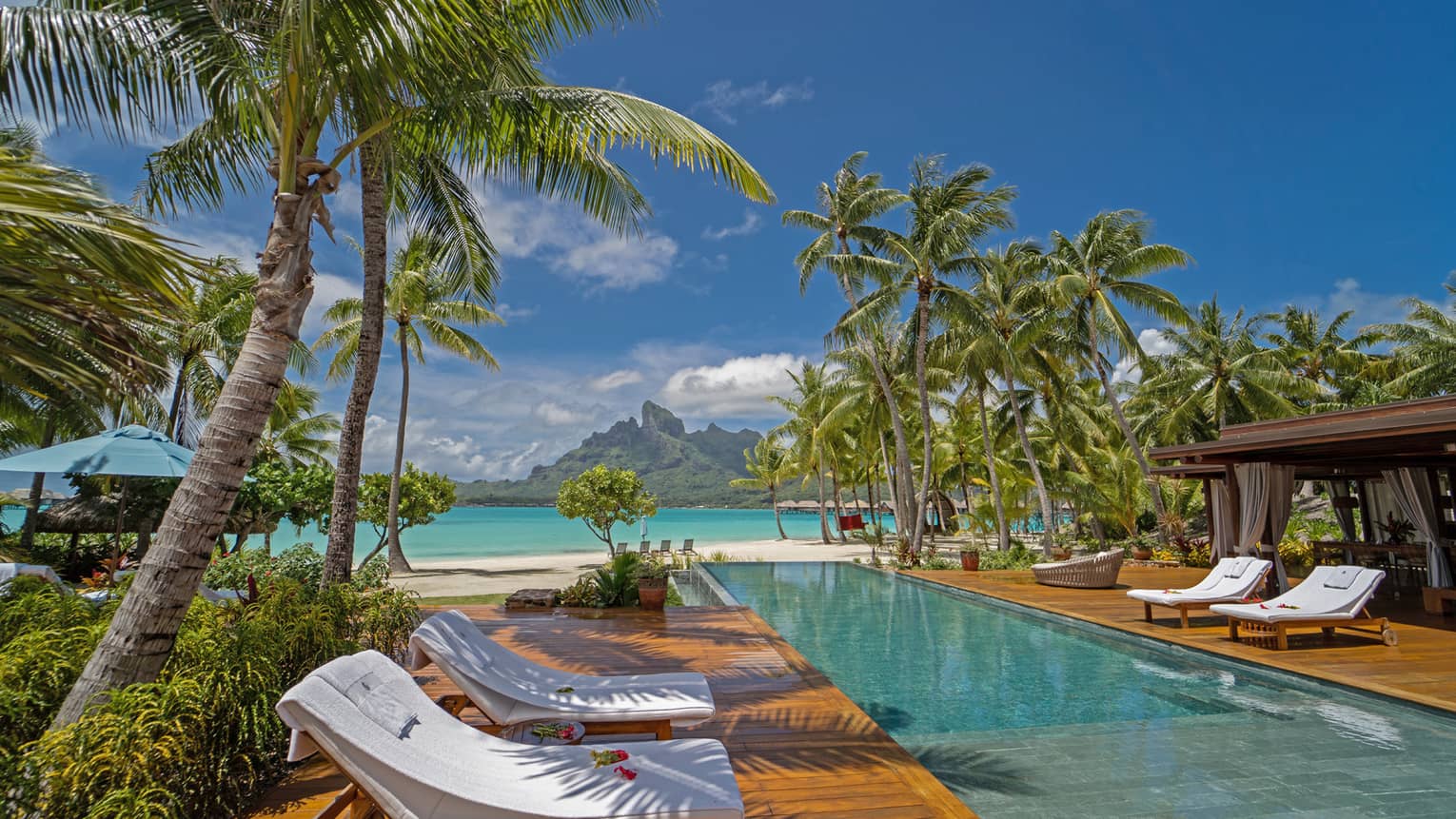 Long rectangular pool with lounge chairs in Bora Bora villa, with view of turquoise lagoon